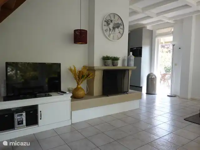 De grote woonkamer is verzien van een gezellige openhaard en tv.